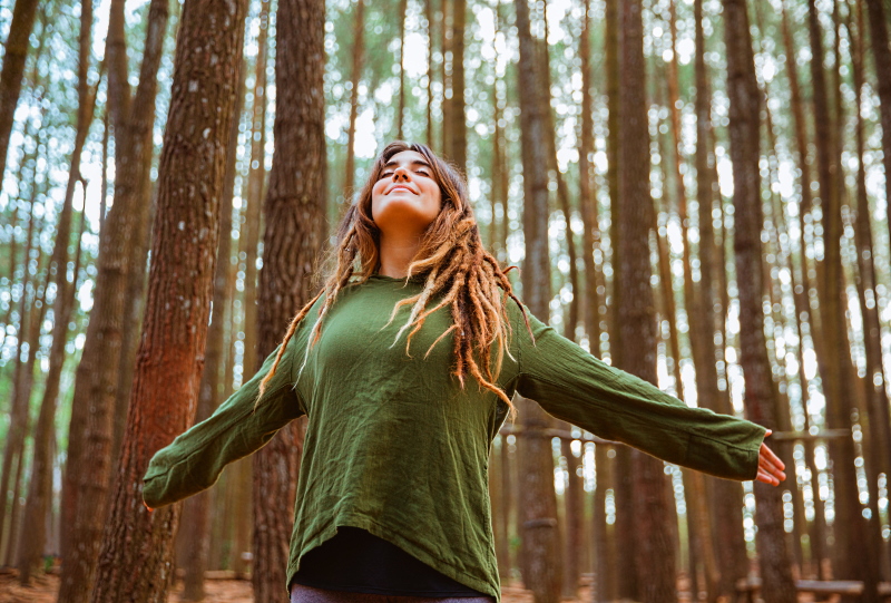 Ragazza che respira a pieni polmoni in un bosco